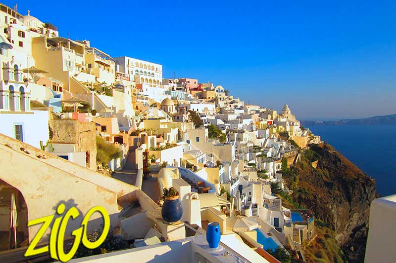 Town of pale houses built along the top of the caldera cliff, the sea far below