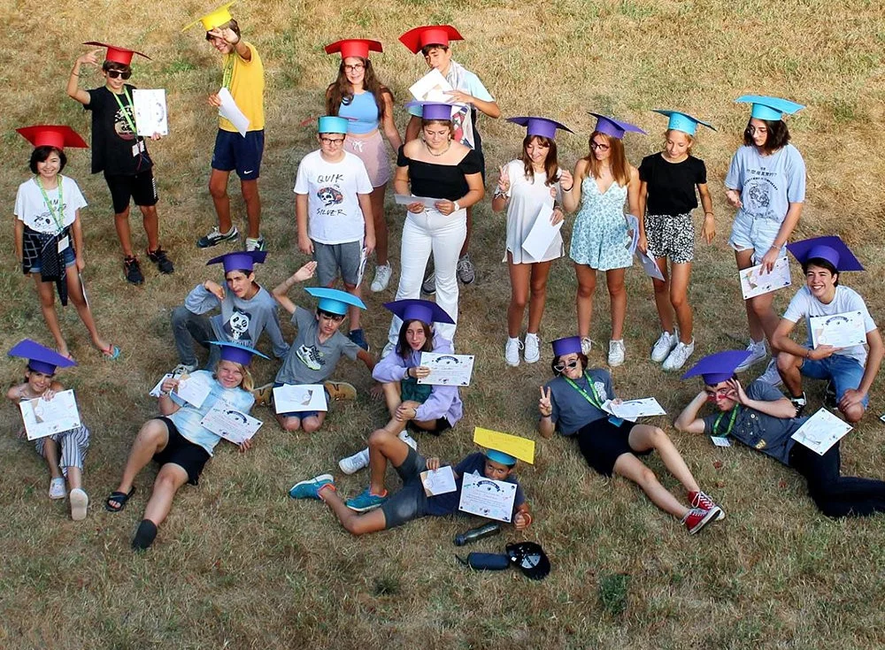Campers on the lawn in graduation caps with their end-of-stay certificates