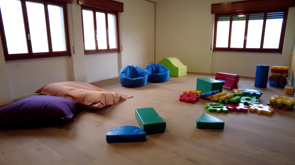 A bright indoor room at Villa Sancelso with floor cushions and soft foam play blocks laid out on the floor between tall shuttered windows